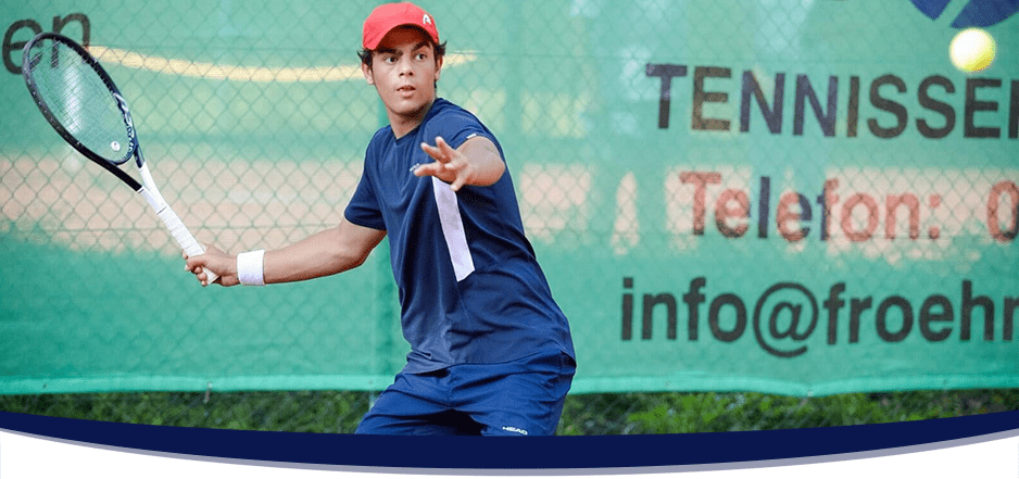 Männlicher Tennisspieler schlägt eine Rückhand auf einem Aschenplatz