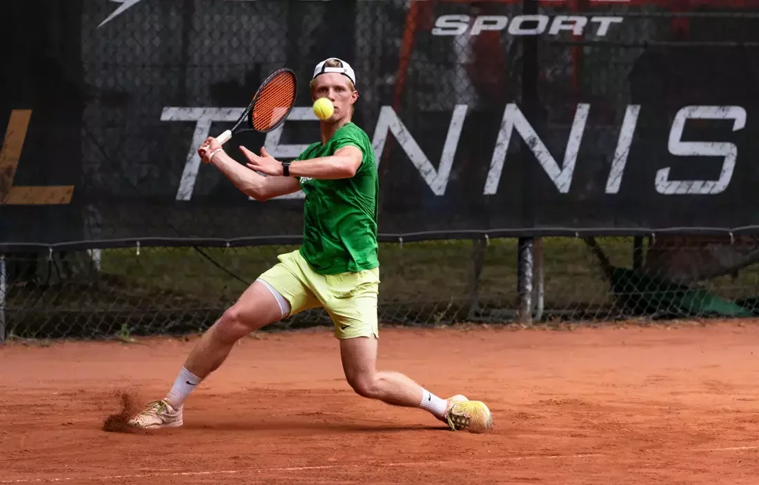 Male tennis player with a blue shirt is ready to retour a serve from the deuce court