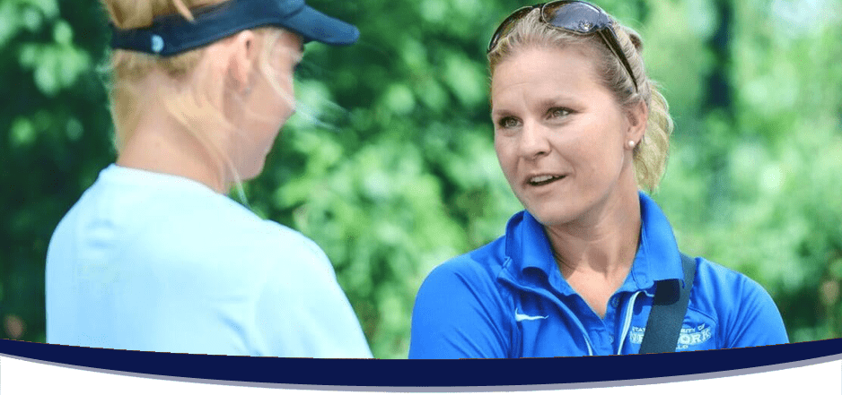 Male college coach in a grey polo shirt talking to a male tennis player in a white shirt