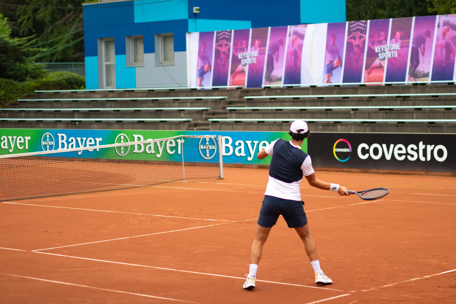 male tennis player in a blue outfit preparing to hit a forehand