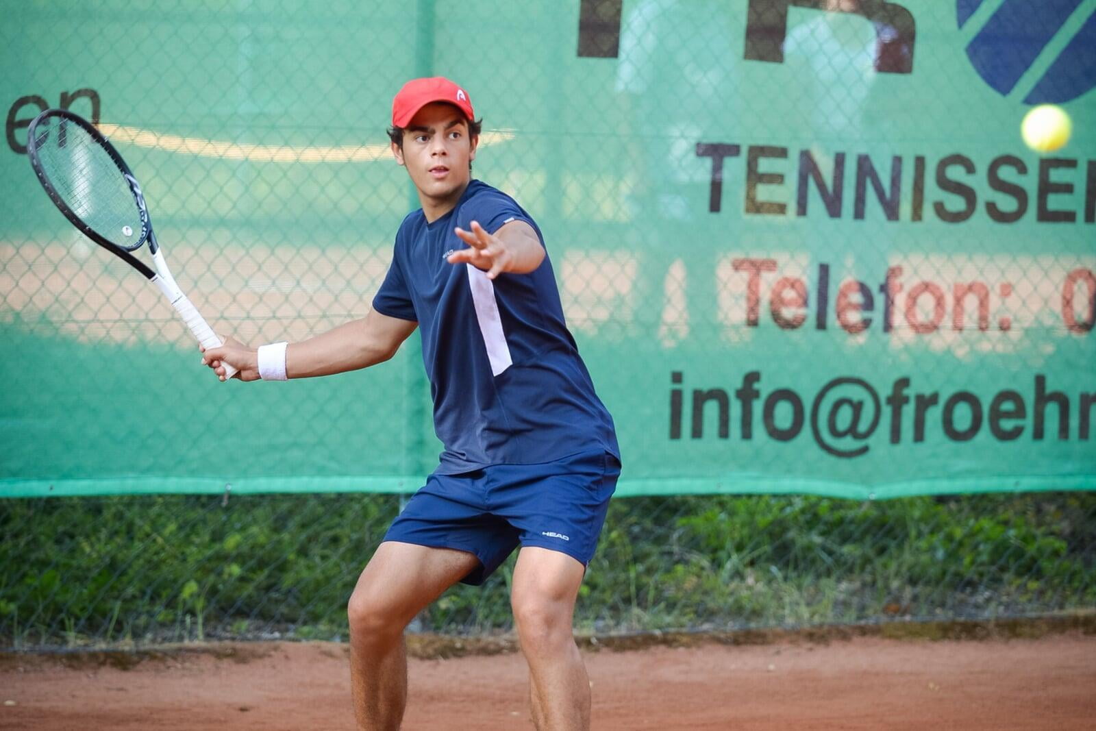 male tennis player in a blue outfit preparing to hit a forehand