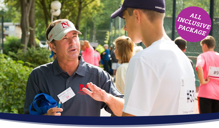 Male college coach in a grey polo shirt talking to a male tennis player in a white shirt