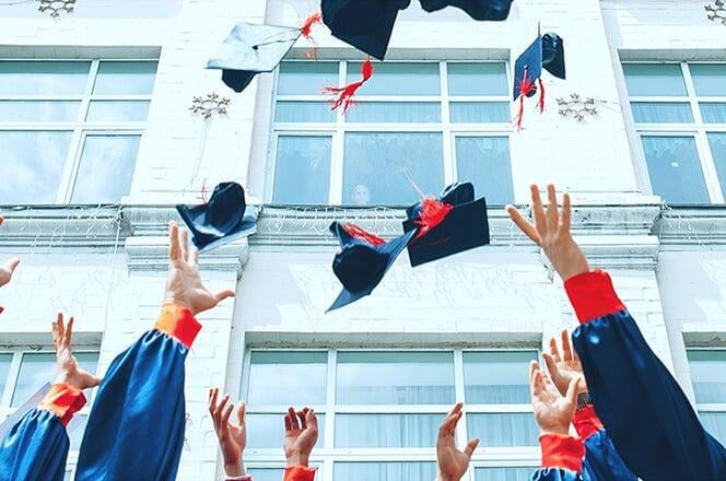 college students throwing their graduation cap into the air